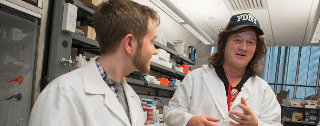 Former doctoral student Cameron McDaniel interacts with researcher Daniel Hassett.